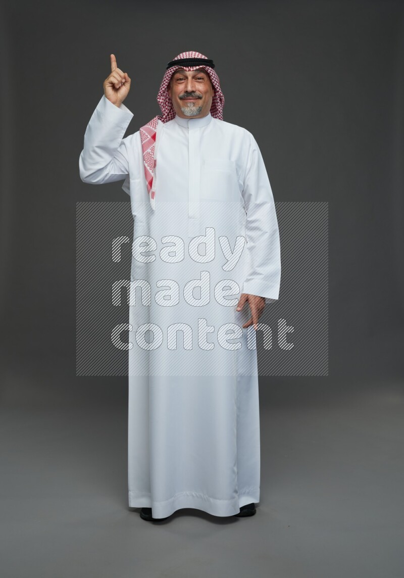 Saudi man with shomag Standing Interacting with the camera on gray background