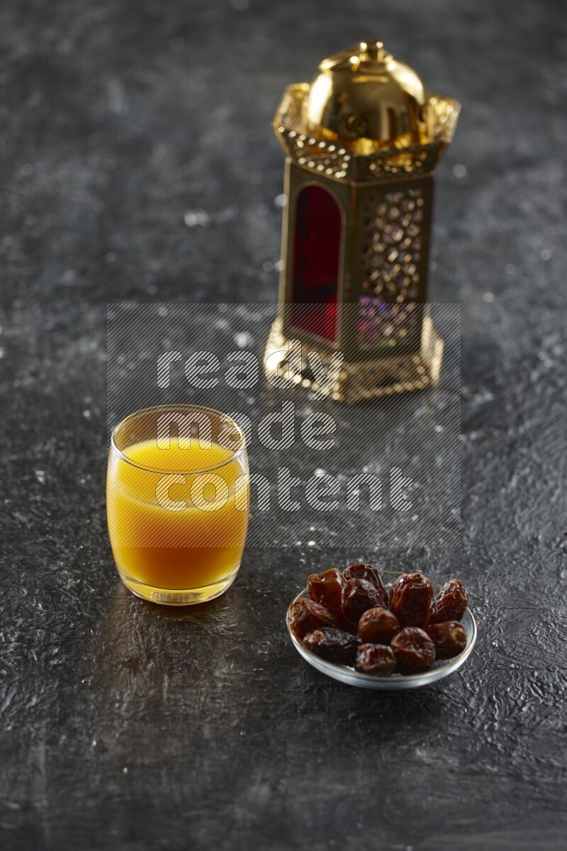 A golden lantern with different drinks, dates, nuts, prayer beads and quran on textured black background