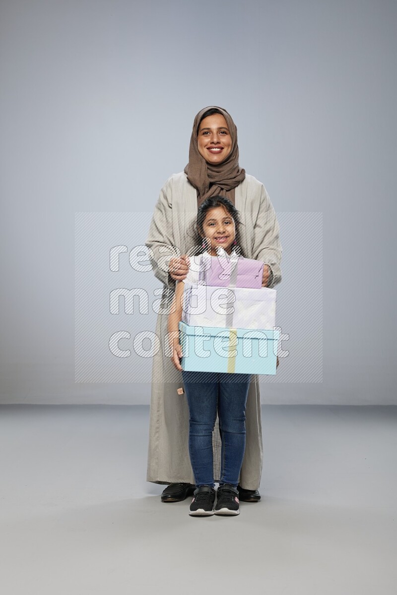 A girl giving a gift to her mother on gray background