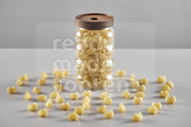 Raw pasta in a glass jar on light grey background