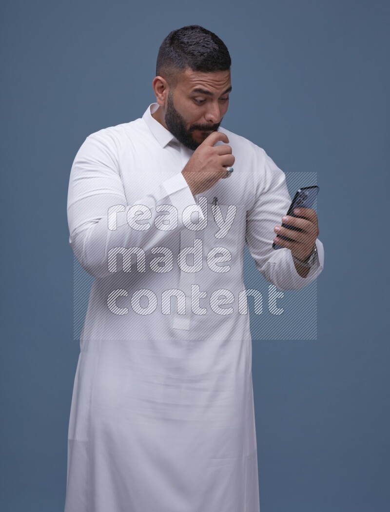 A man Texting on Blue Background wearing Saudi Thob