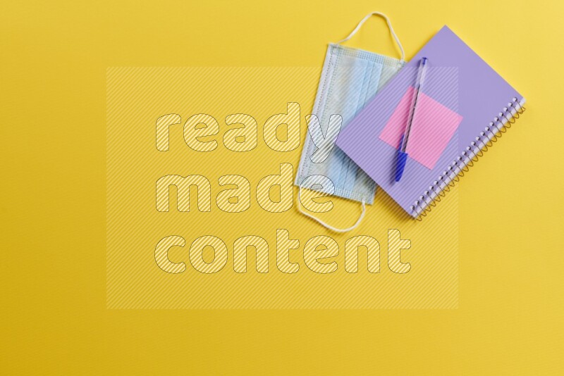 A purple notebook with different school supplies on yellow background