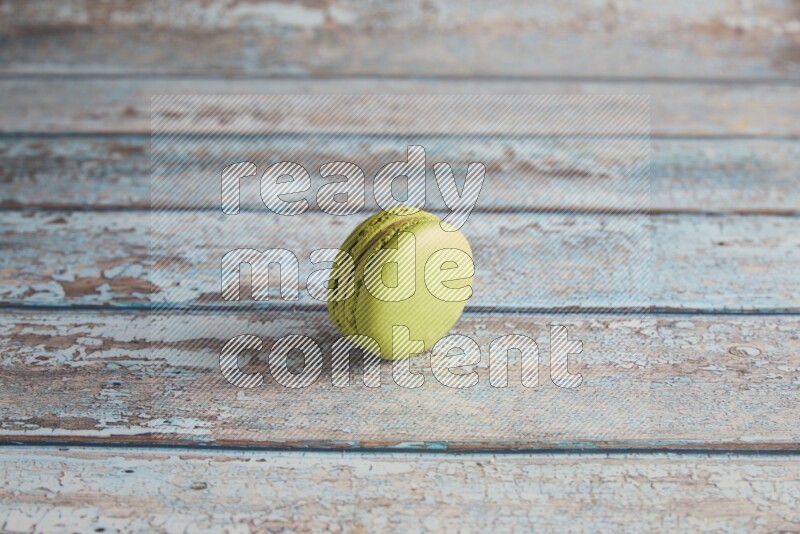 45º Shot of Green Pistachio macaron on light blue wooden background