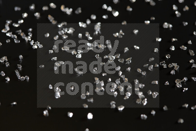 Silver shimmering fragments of glass scattered on a black background