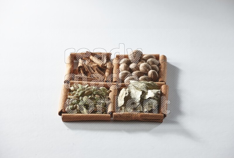 4 squares of cinnamon sticks full of nutmegs, bay laurel leaves, cardamom and cinnamon on white flooring