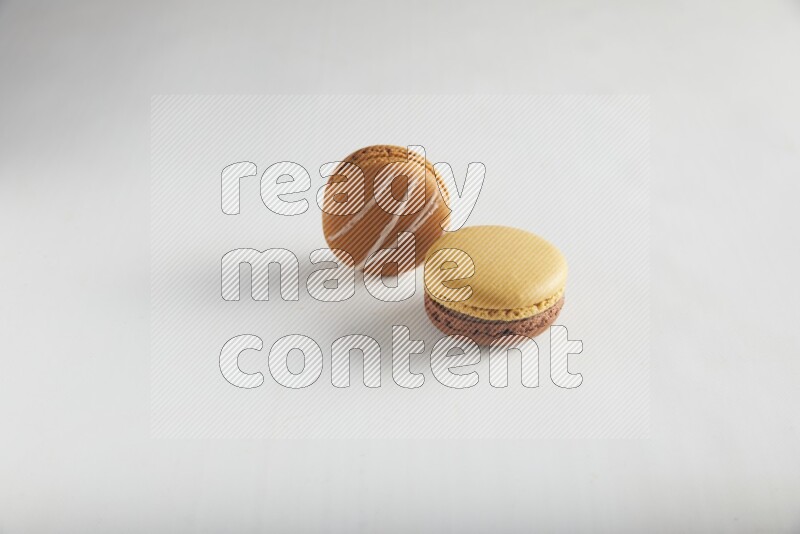 45º Shot of of two assorted Brown Irish Cream, and Yellow, and Brown Chai Latte macarons on white background