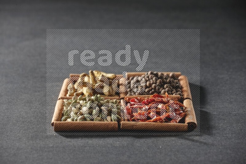 4 squares of cinnamon sticks full of cardamom, dried red chilis, allspice and turmeric fingers on black flooring