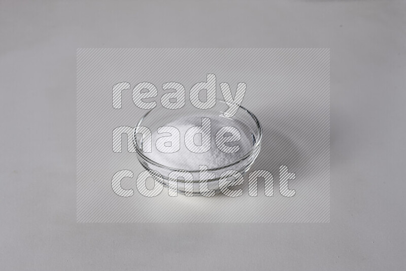 A glass bowl full of fine table salt on white background