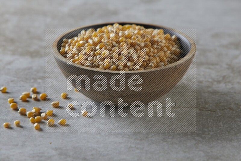 corn kernel in a wooden bowl on a grey textured countertop