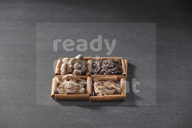 4 squares of cinnamon sticks full of coffee beans, cinnamon, dried ginger and nutmegs on black flooring