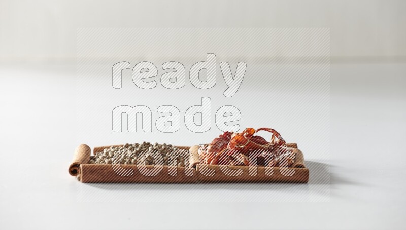 2 squares of cinnamon sticks full of red dried chilis and white pepper on white flooring