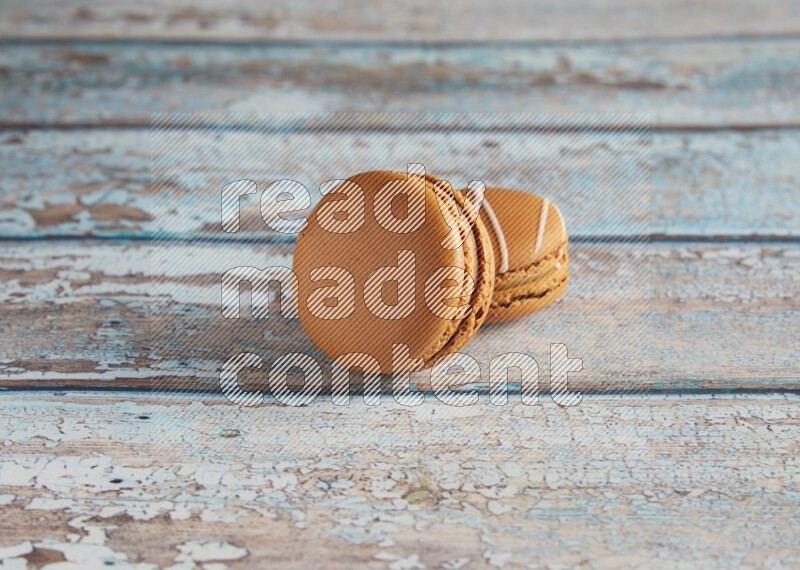 45º Shot of of two assorted Brown Irish Cream, and Brown Maple Taffy macarons  on light blue background
