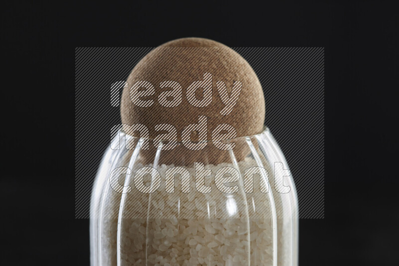 White rice in a glass jar on black background