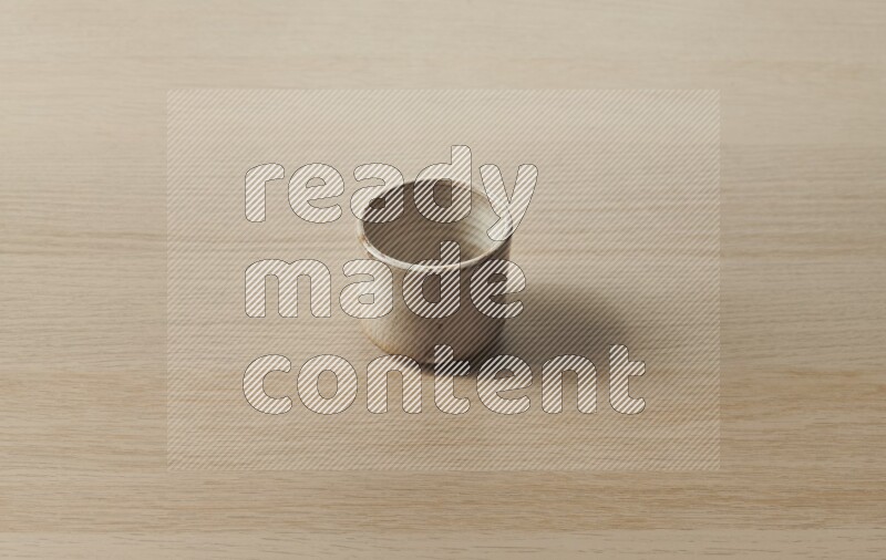 A pottery cup on light wooden background