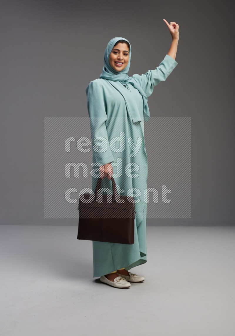 Saudi Woman wearing Abaya standing holding bag on Gray background