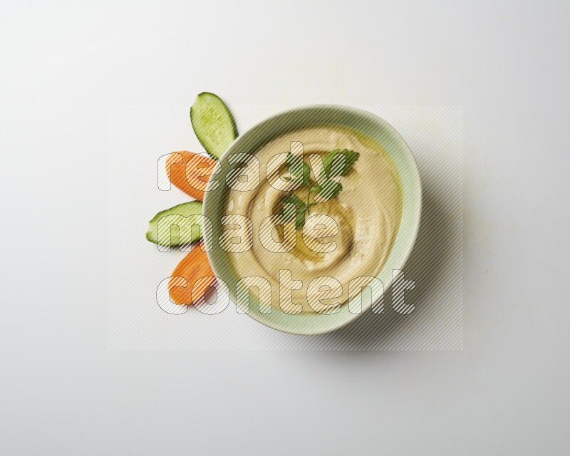 Hummus in a green plate garnished with parsley on a white background