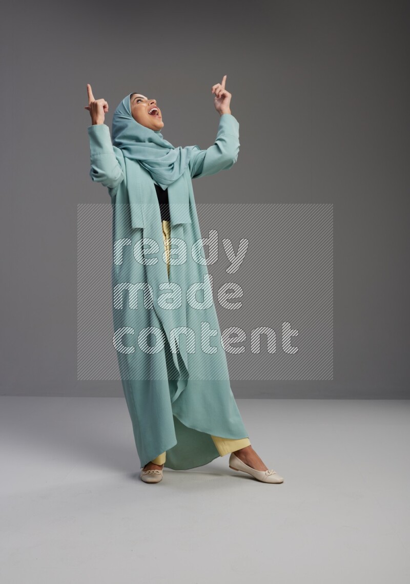Saudi Woman wearing Abaya standing interacting with the camera on Gray background