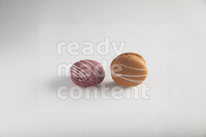 45º Shot of of two assorted Brown Irish Cream, and Red Poppy Flower macarons on white background