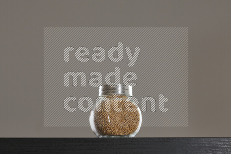 بذور الخردل في وعاء زجاجي على خلفية سوداء