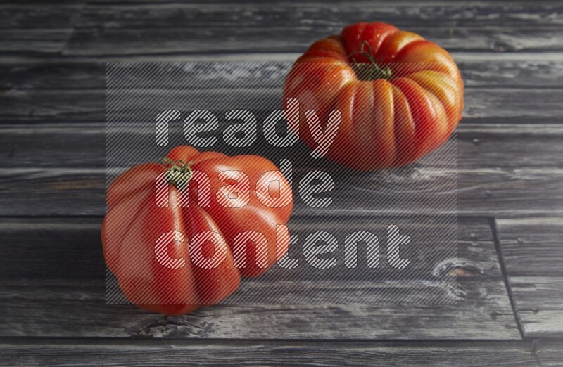 45 degree two heirloom tomato on a textured grey wooden background