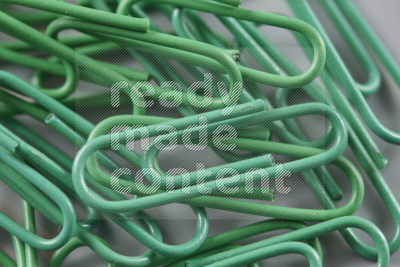 Green paper clips isolated on a grey background