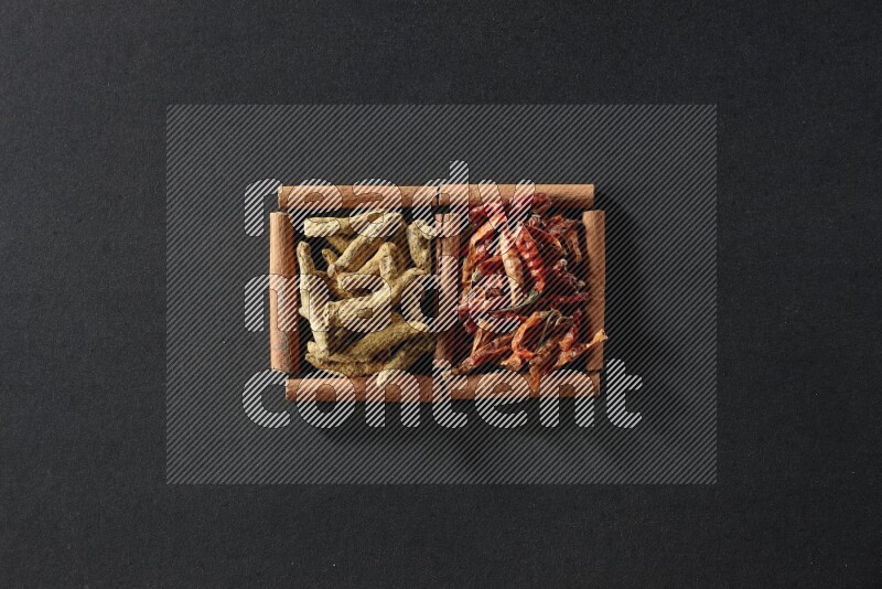 2 squares of cinnamon sticks full of chilis and turmeric fingers on black flooring