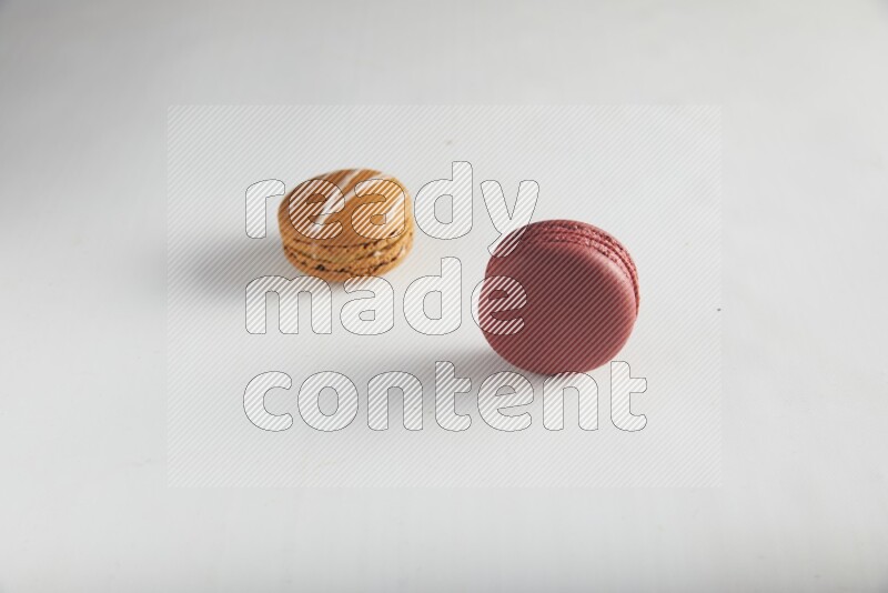 45º Shot of of two assorted Brown Irish Cream, and Red Velvet macarons on white background