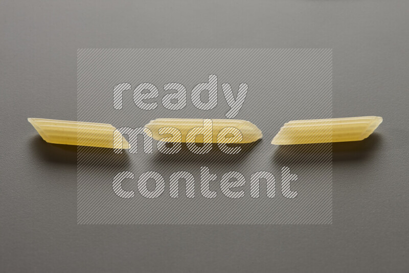 Mini penne pasta on grey background