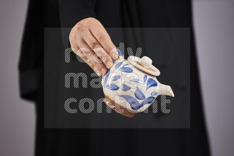 A woman in black abaya holding different pottery essentials in different positions