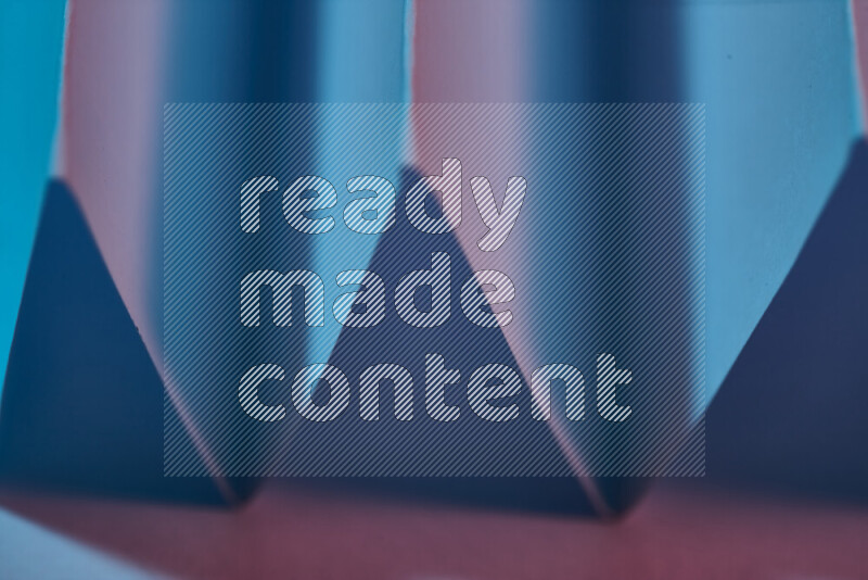 A close-up abstract image showing sharp geometric paper folds in blue and pink gradients