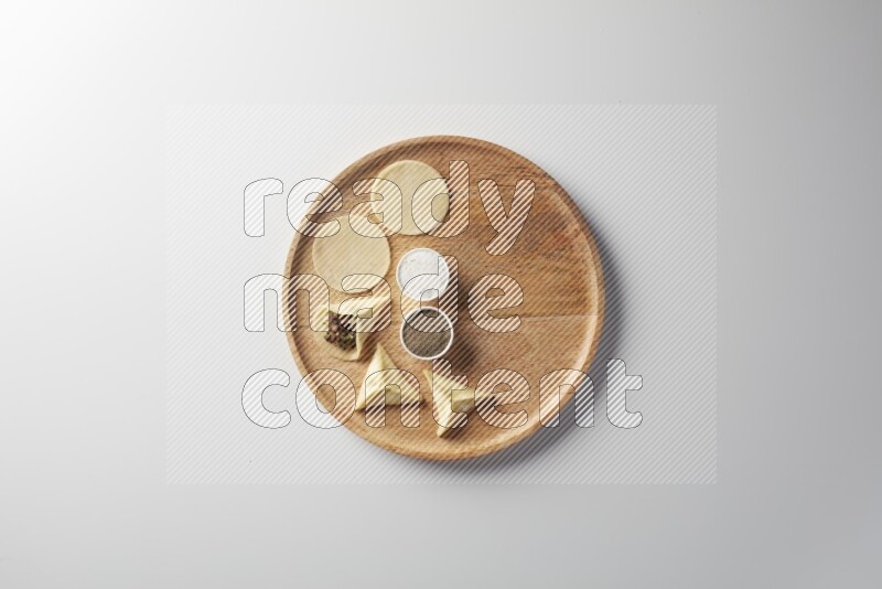 two closed sambosas and one open sambosa filled with meat while salt and black pepper aside in a wooden dish on a white background