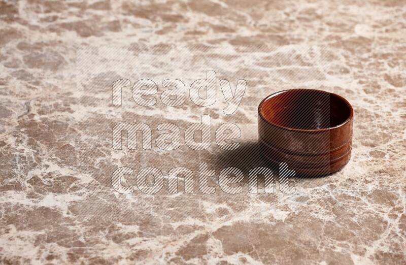 A brown pottery bowl on beige marble background
