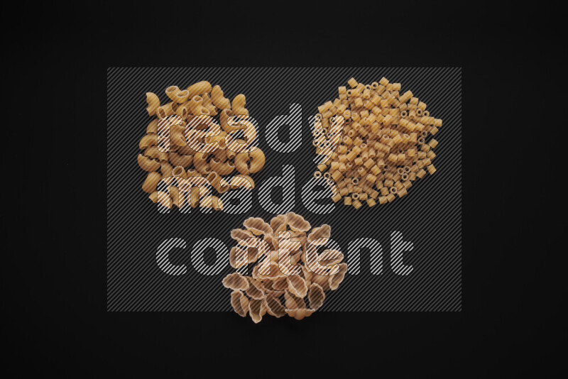 Different pasta types in bunches on black background