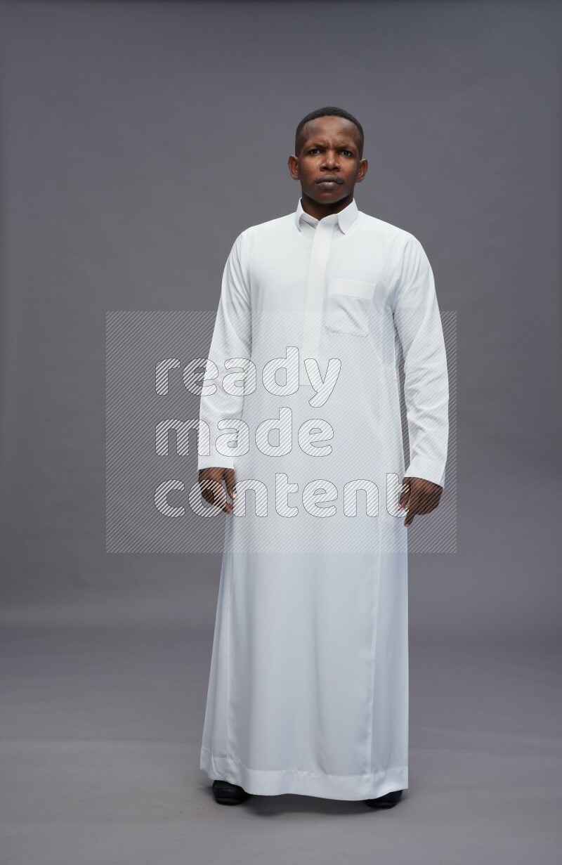 Saudi man wearing thob standing interacting with the camera on gray background
