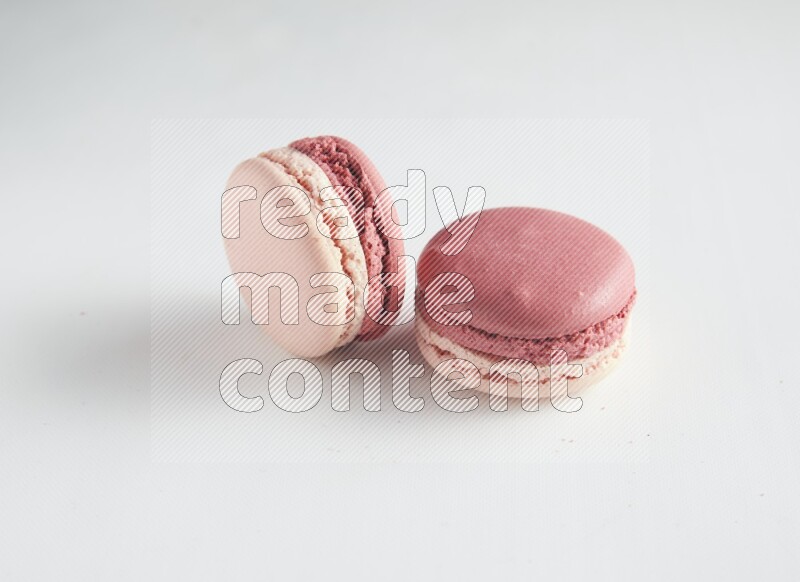 45º Shot of two Pink Litchi Raspberry macarons on white background
