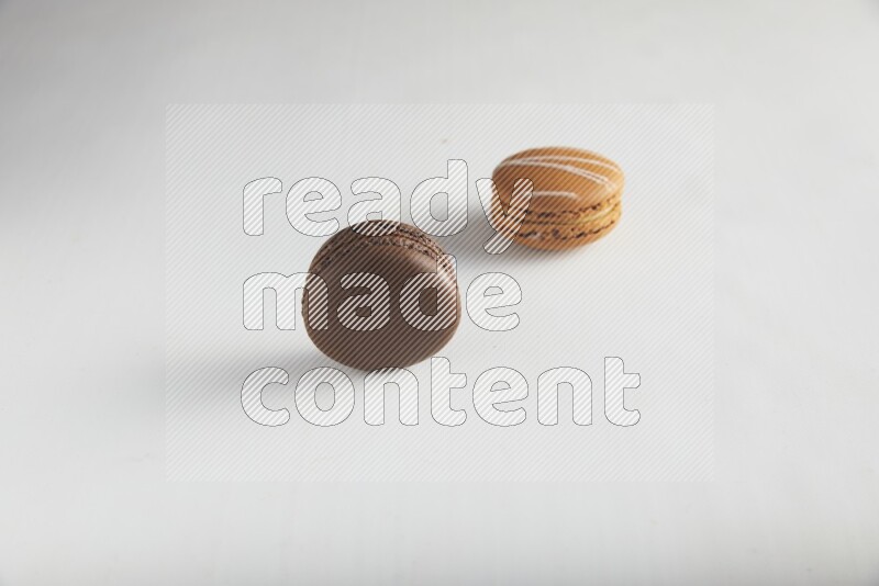 45º Shot of of two assorted Brown Irish Cream, and Brown Dark Chocolate macarons on white background