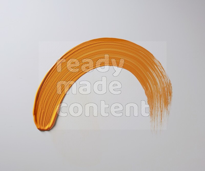 An orange half circular painting brush stroke on white background