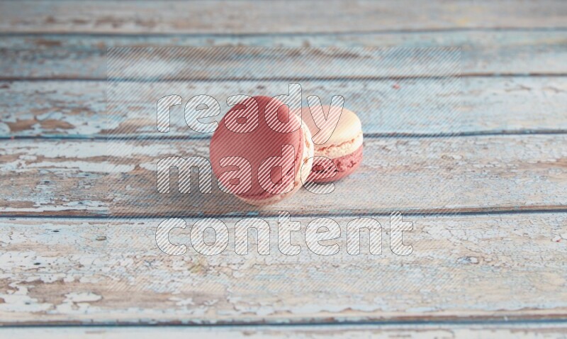 45º Shot of two Pink Litchi Raspberry macarons on light blue wooden background