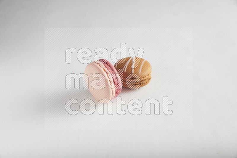 45º Shot of of two assorted Brown Irish Cream, and Pink Litchi Raspberry macarons on white background