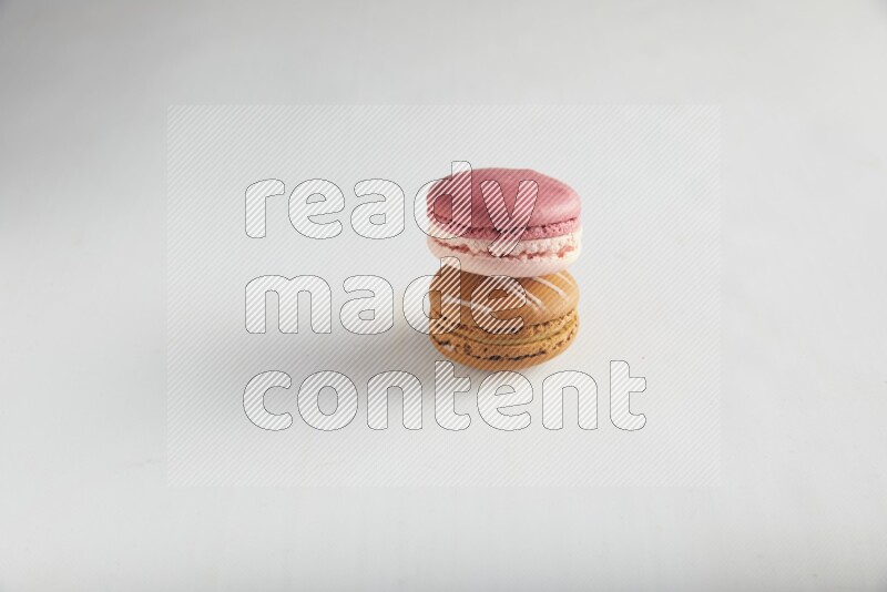 45º Shot of of two assorted Brown Irish Cream, and Pink Litchi Raspberry macarons on white background