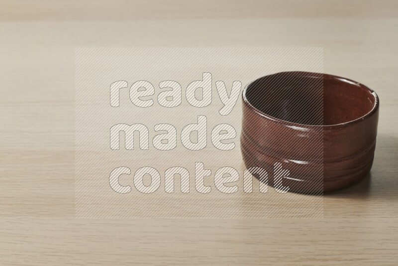 A brown pottery bowl on light wooden background