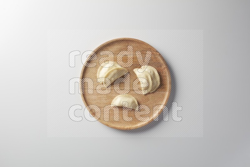 Five Sambosas on a wooden round plate on a white background