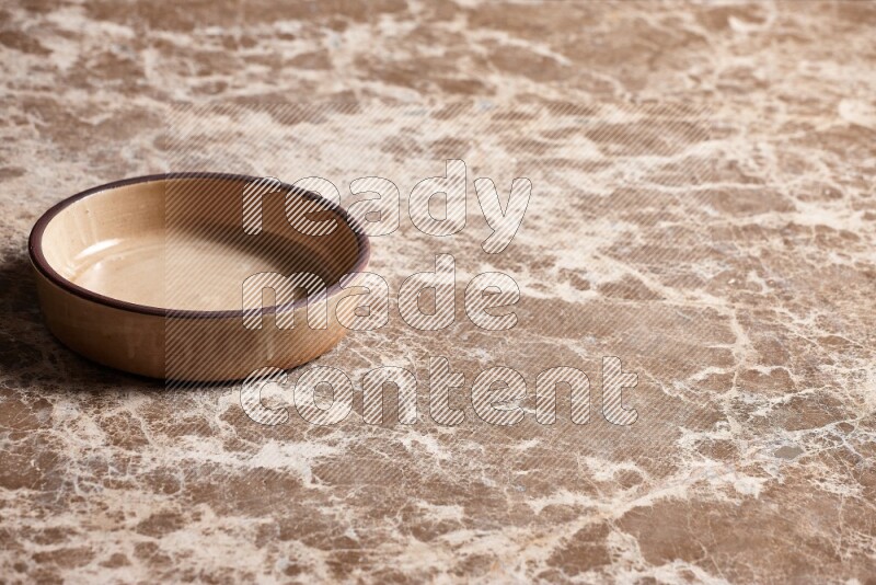 A beige pottery oven plate on beige marble background