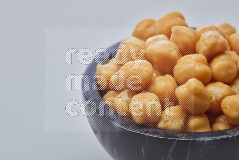 Close up shot of boiled chickpeas in a container on white background