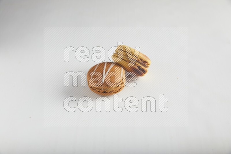45º Shot of of two assorted Brown Irish Cream, and Yellow Crème Brulée macarons on white background
