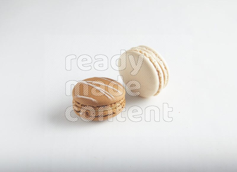 45º Shot of of two assorted Brown Irish Cream, and White Caramel fleur de sel macarons on white background