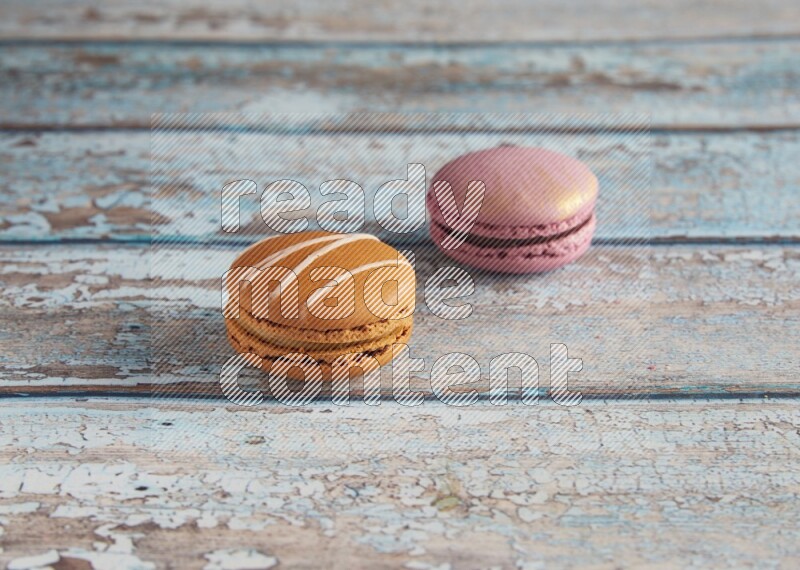 45º Shot of of two assorted Brown Irish Cream, and Purple Strawberry macarons  on light blue background
