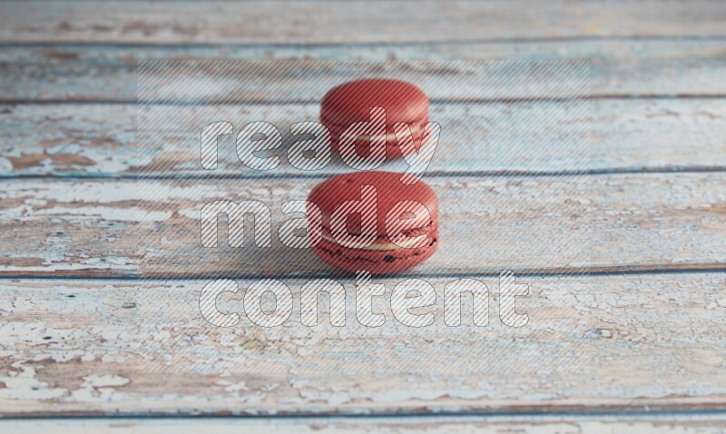 45º Shot of two Red Velvet macarons on light blue wooden background