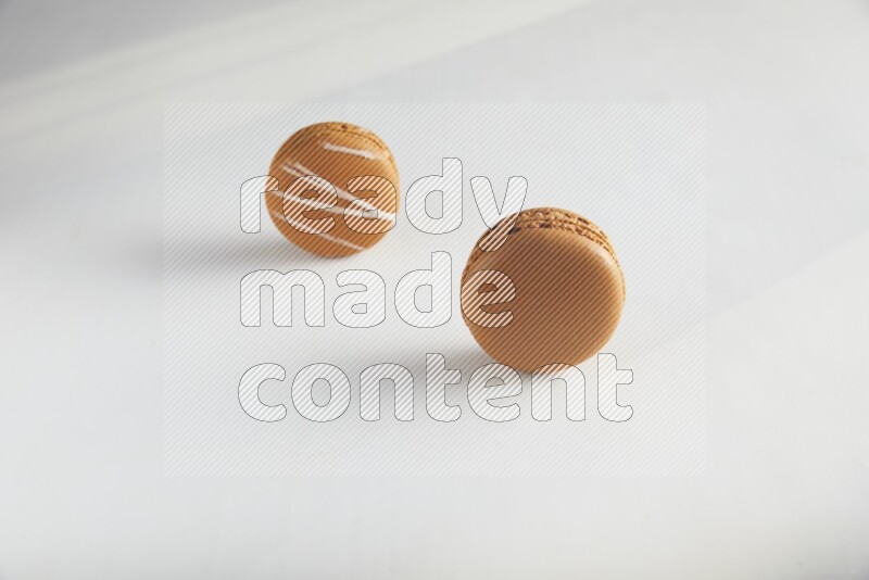 45º Shot of of two assorted Brown Irish Cream, and Brown Maple Taffy macarons  on white background