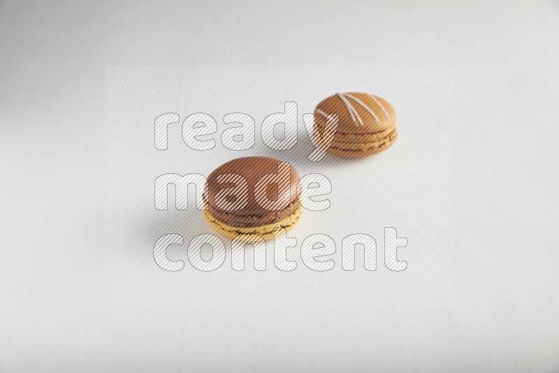 45º Shot of of two assorted Brown Irish Cream, and Yellow, and Brown Chai Latte macarons on white background